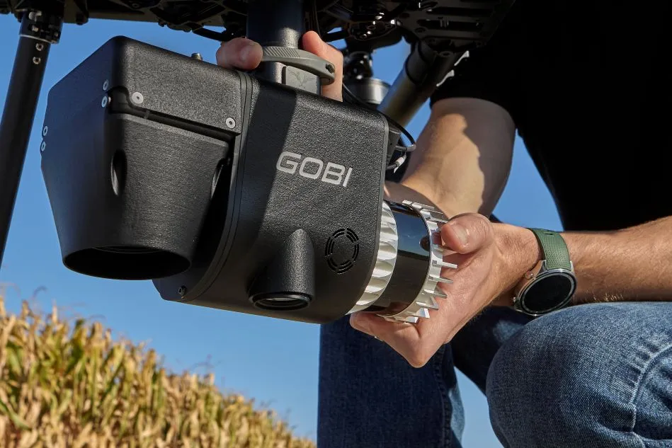 Person Adjusting GOBI Device Outdoors Near Vegetation
